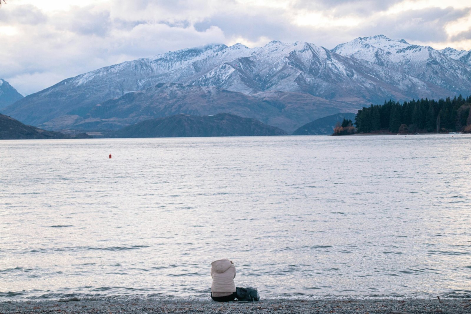 a person sitting on the shore of a lake