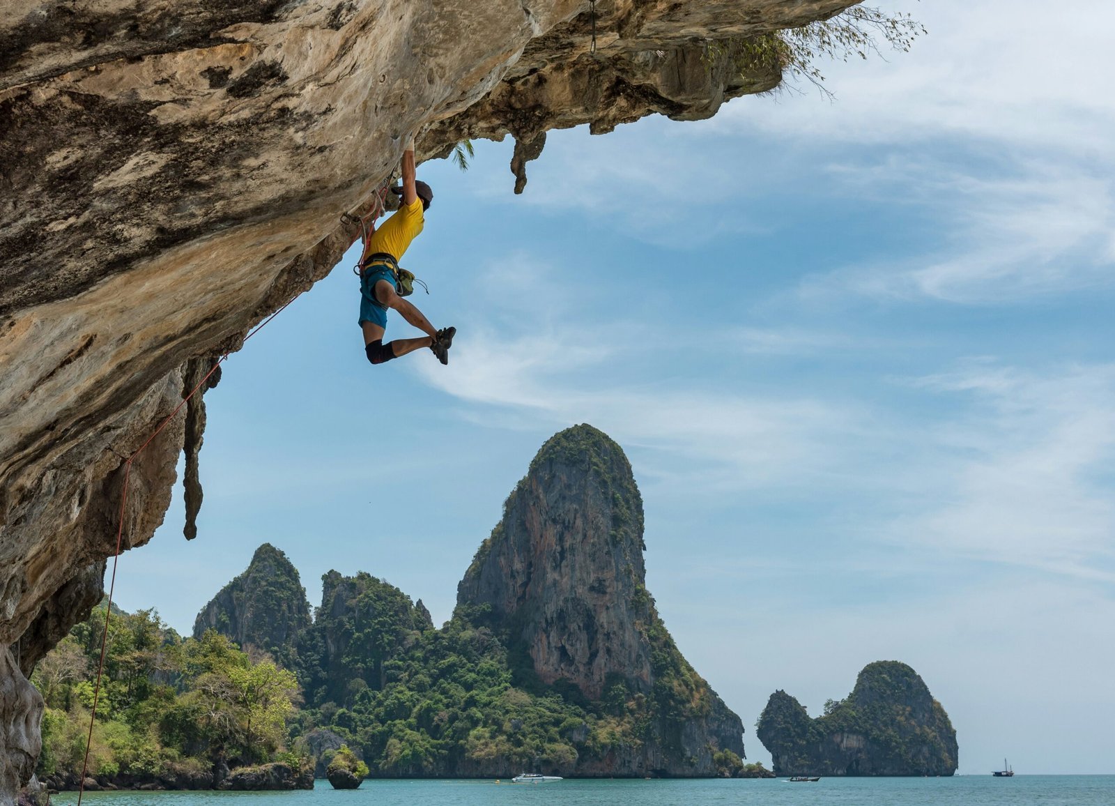 man climbing cliff beside beach